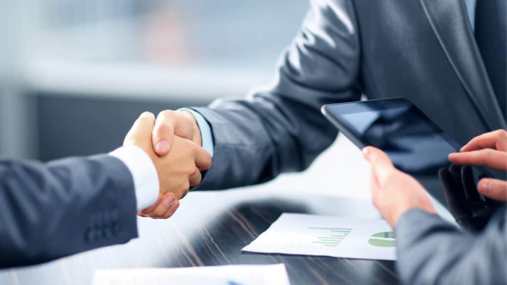 Dos empresarios se dan la mano en una mesa durante una reunión de Servicios.